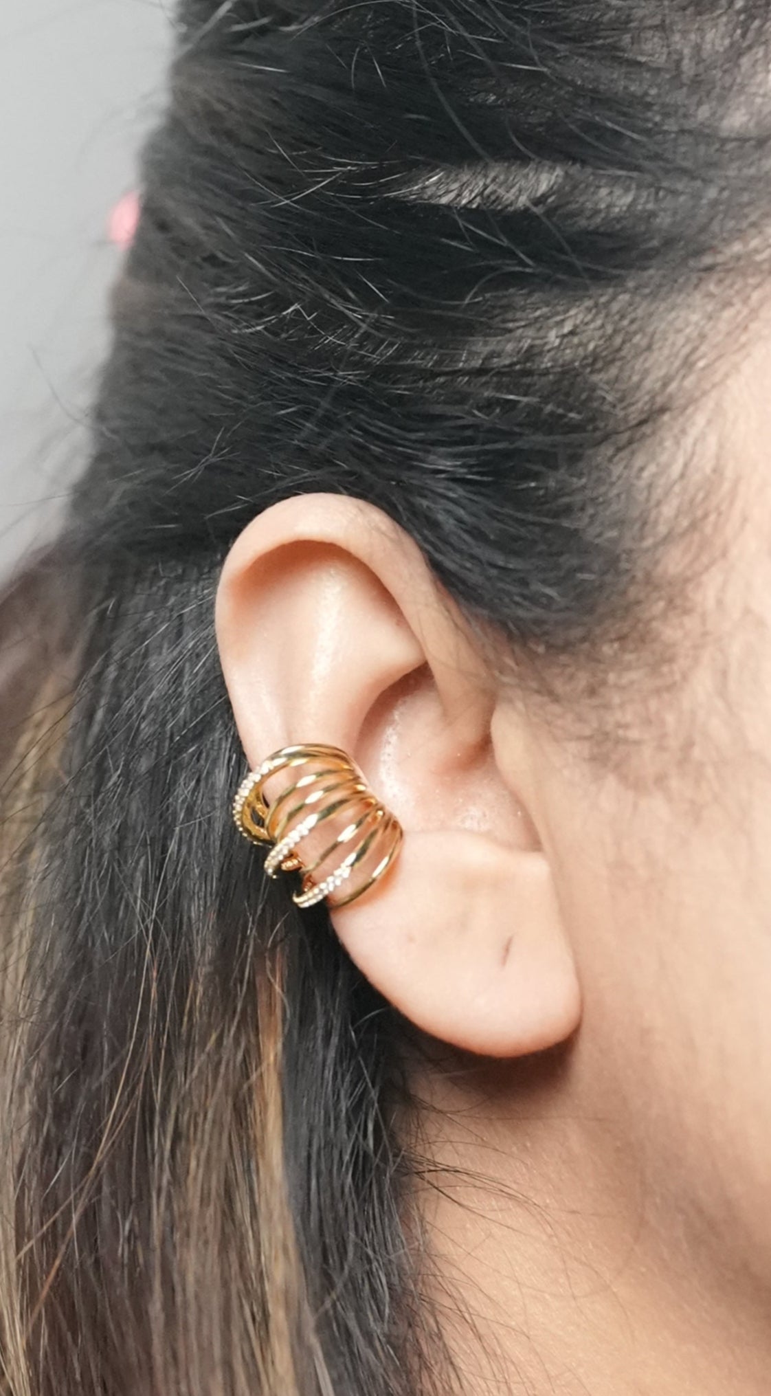 A young girl in her 20s wearing a gold plated ear cuff of Adiva Jewelry in one ear