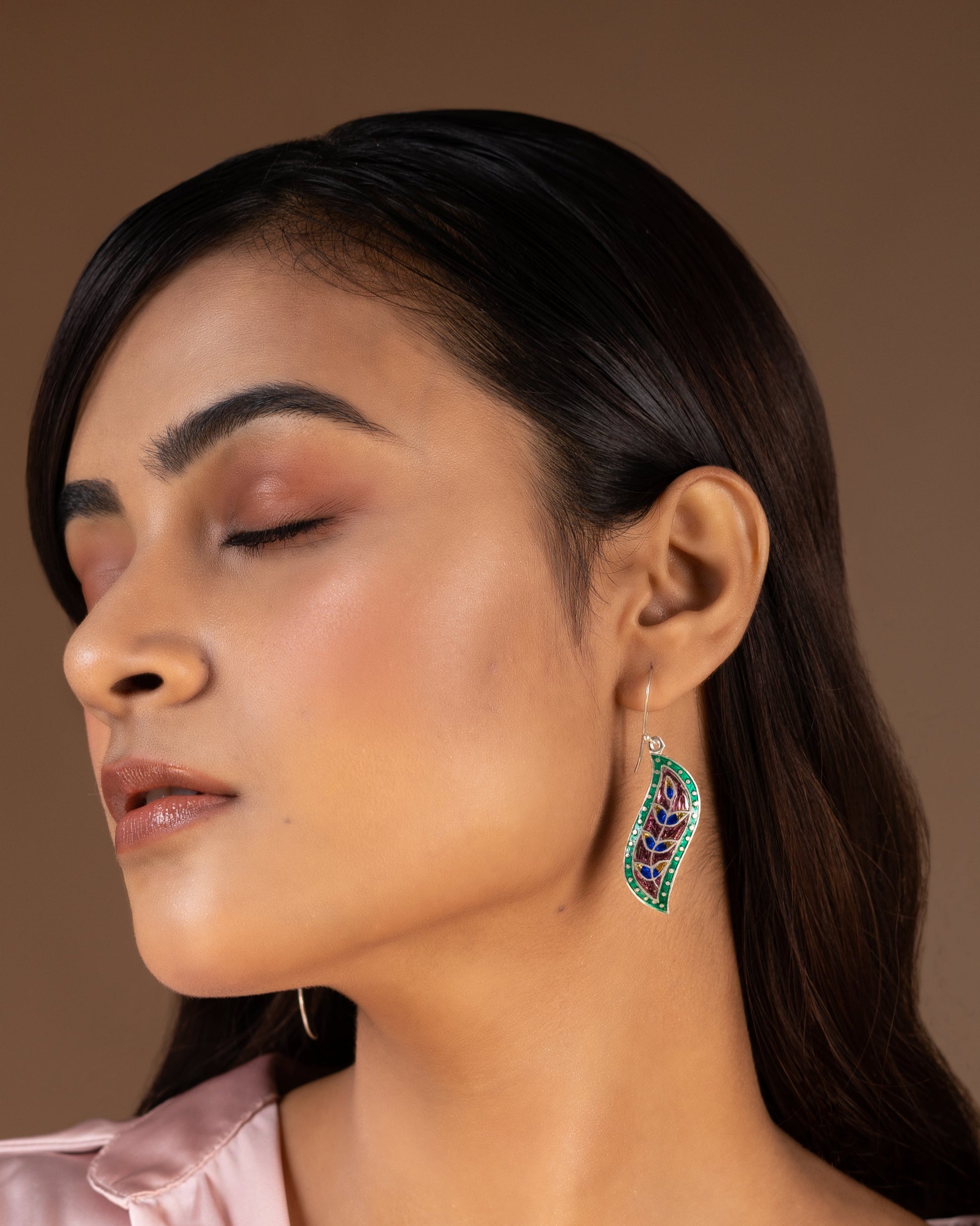 Close-up of a woman wearing a decorative earring made of fine silver by Adiva Jewelry 