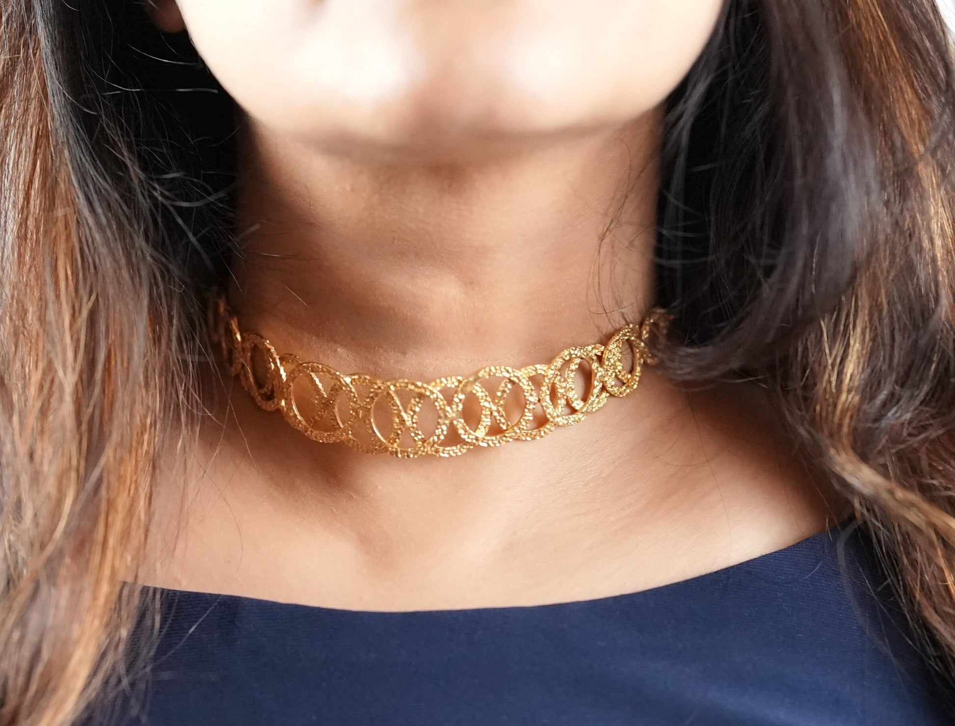 Model wearing a handcrafted gold-toned choker necklace with interlocking oval loops – statement semi-fine jewelry by Adiva Jewelry