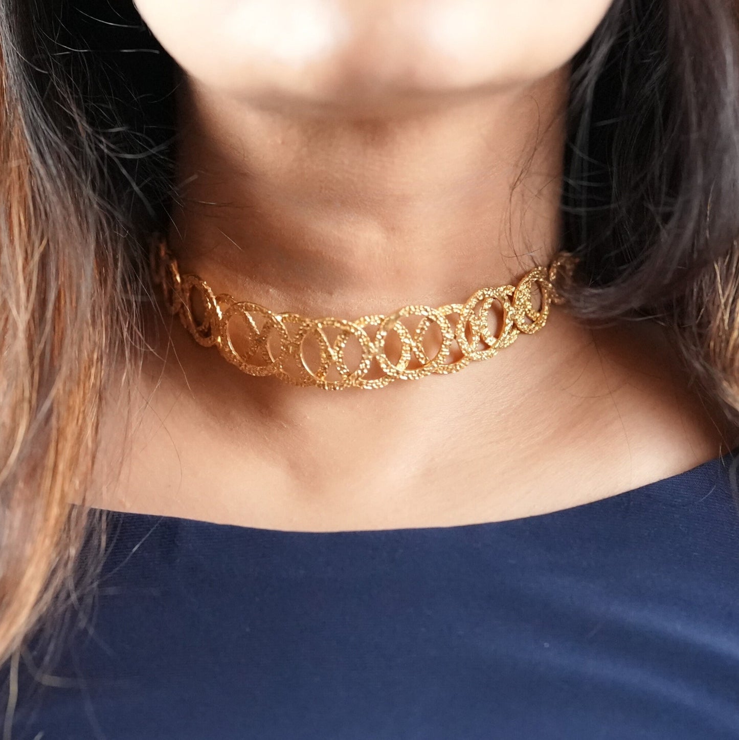 Woman in her 30s wearing a handcrafted gold-toned choker necklace with interlocking oval loops – statement semi-fine jewelry by Adiva Jewelry