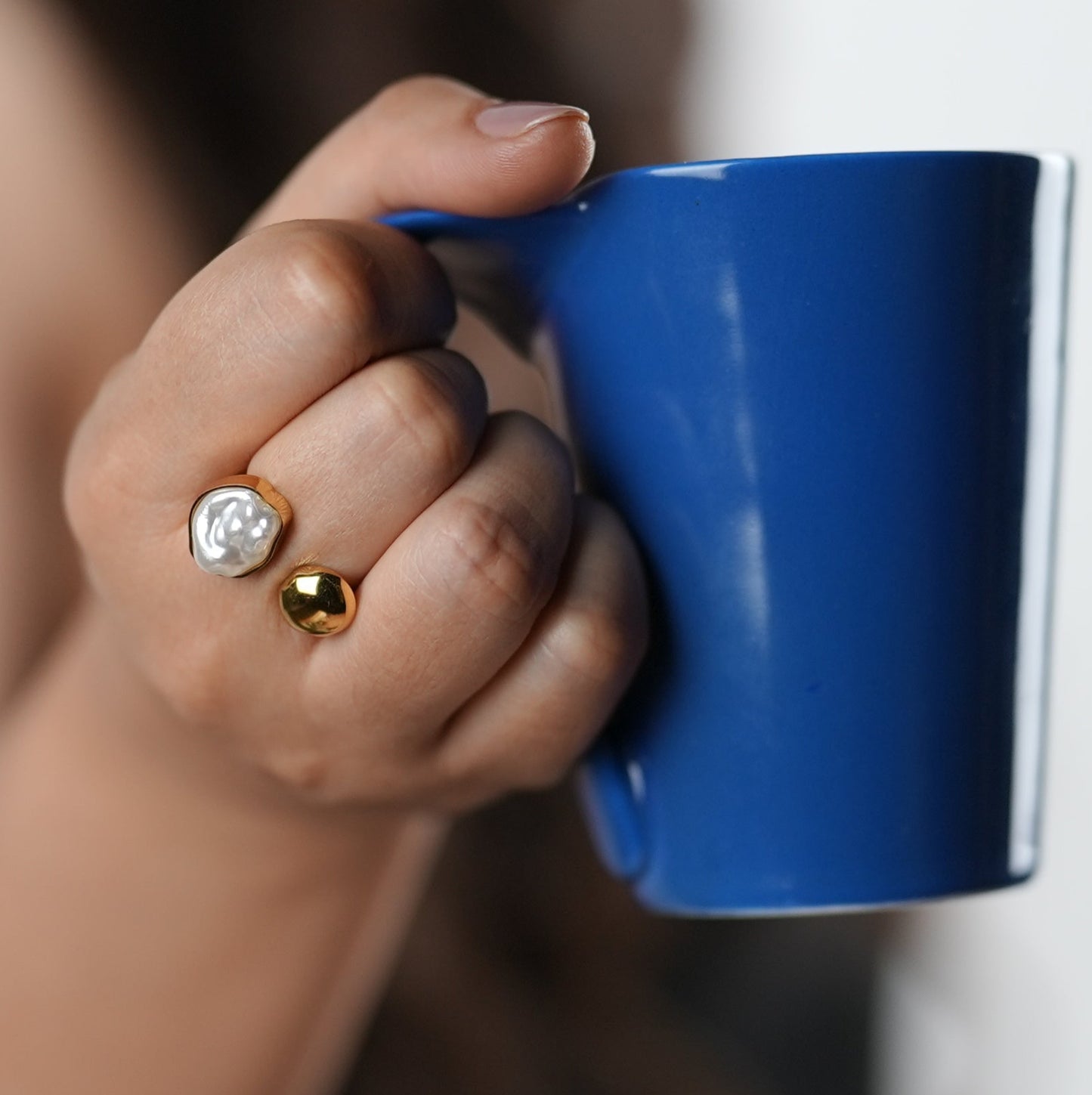 Gold-tone open band statement ring with asymmetrical pearl and molten metal detailing, worn on hand — Adiva Jewelry lifestyle accessory.