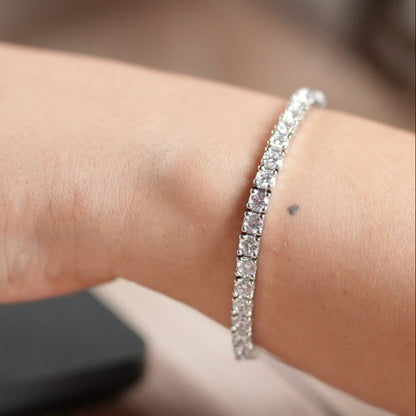 Woman in a corporate office working on a laptop wearing a tennis bracelet set in sterling silver with high rhodium polish - by Adiva Jewelry 
