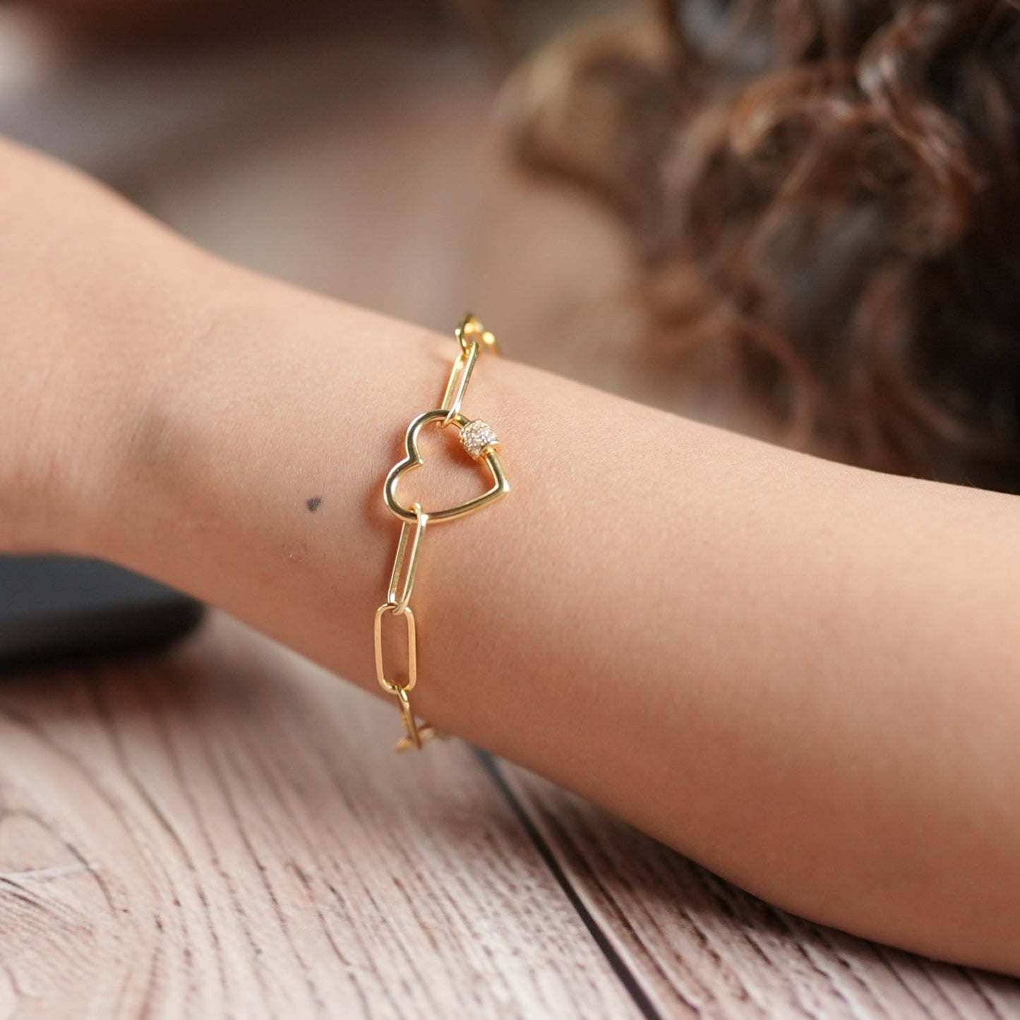 Lady working in a corporate office on a laptop wearing a heart shaped bracelet that is in silver with gold plating - handcrafted by Adiva Jewelry