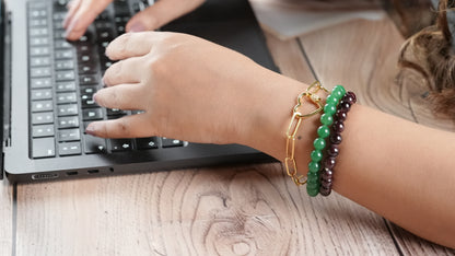Lady working in a corporate office on a laptop wearing a heart shaped bracelet that is made in silver with a  and gold plating - handcrafted by Adiva Jewelry