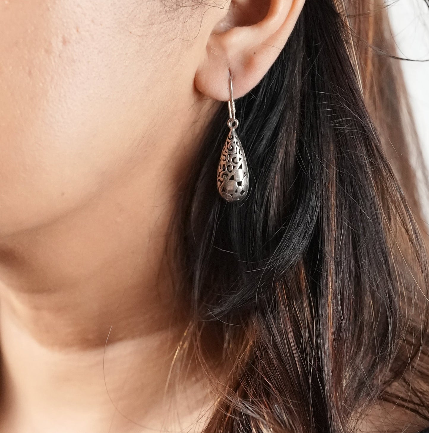 Close-up of a woman wearing an oxidized silver earring with her daily wear outfit. Earring is from Adiva Jewelry