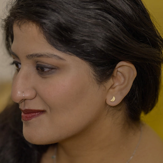 Close-up of a woman wearing a half moon earring made out of sterling silver and gold plating 