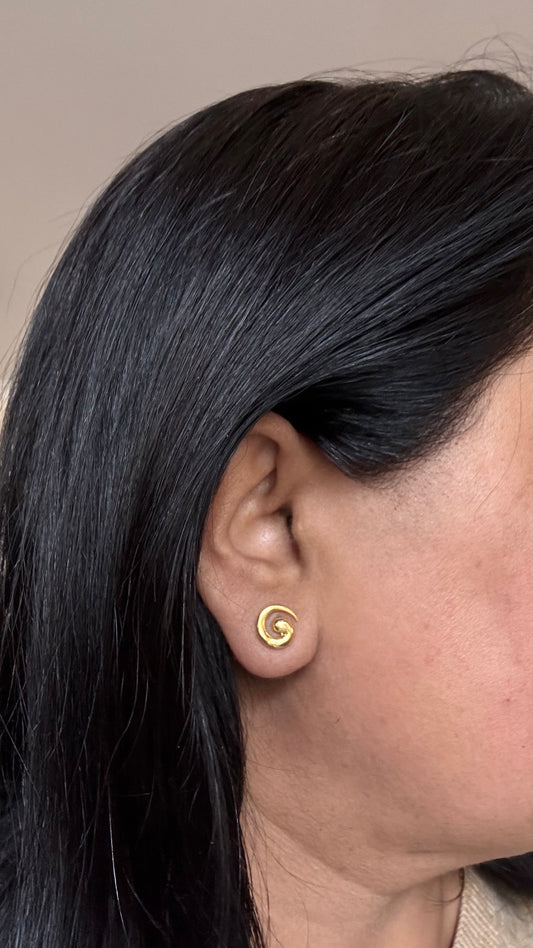 Close-up of a woman's ear wearing a swirl shaped earring 