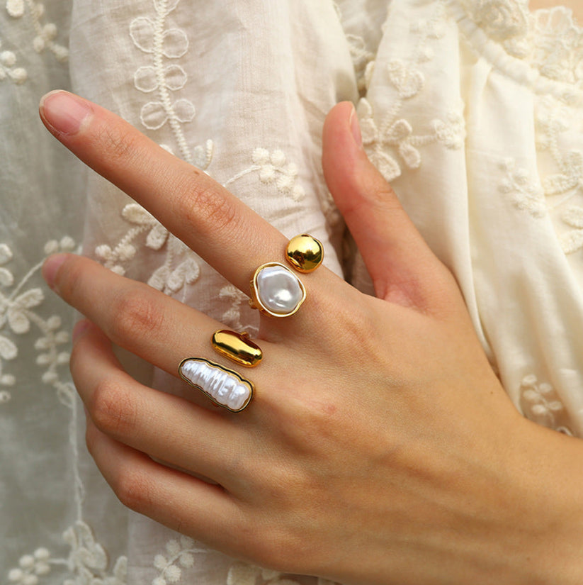 Elegant gold-tone statement rings with abstract pearl and molten metal designs, styled on hand for Adiva Jewelry — a modern lifestyle jewelry brand celebrating artistic fashion.